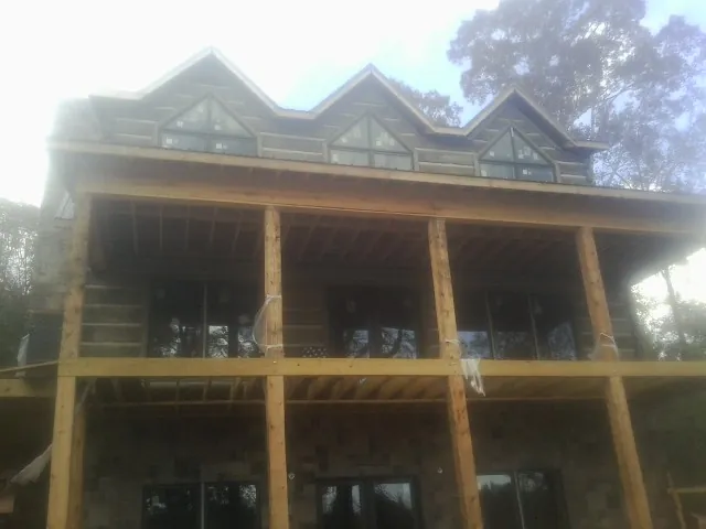 Dormers and porch framing on a large log home under construction — Roof Coating work by our crew in Desmet