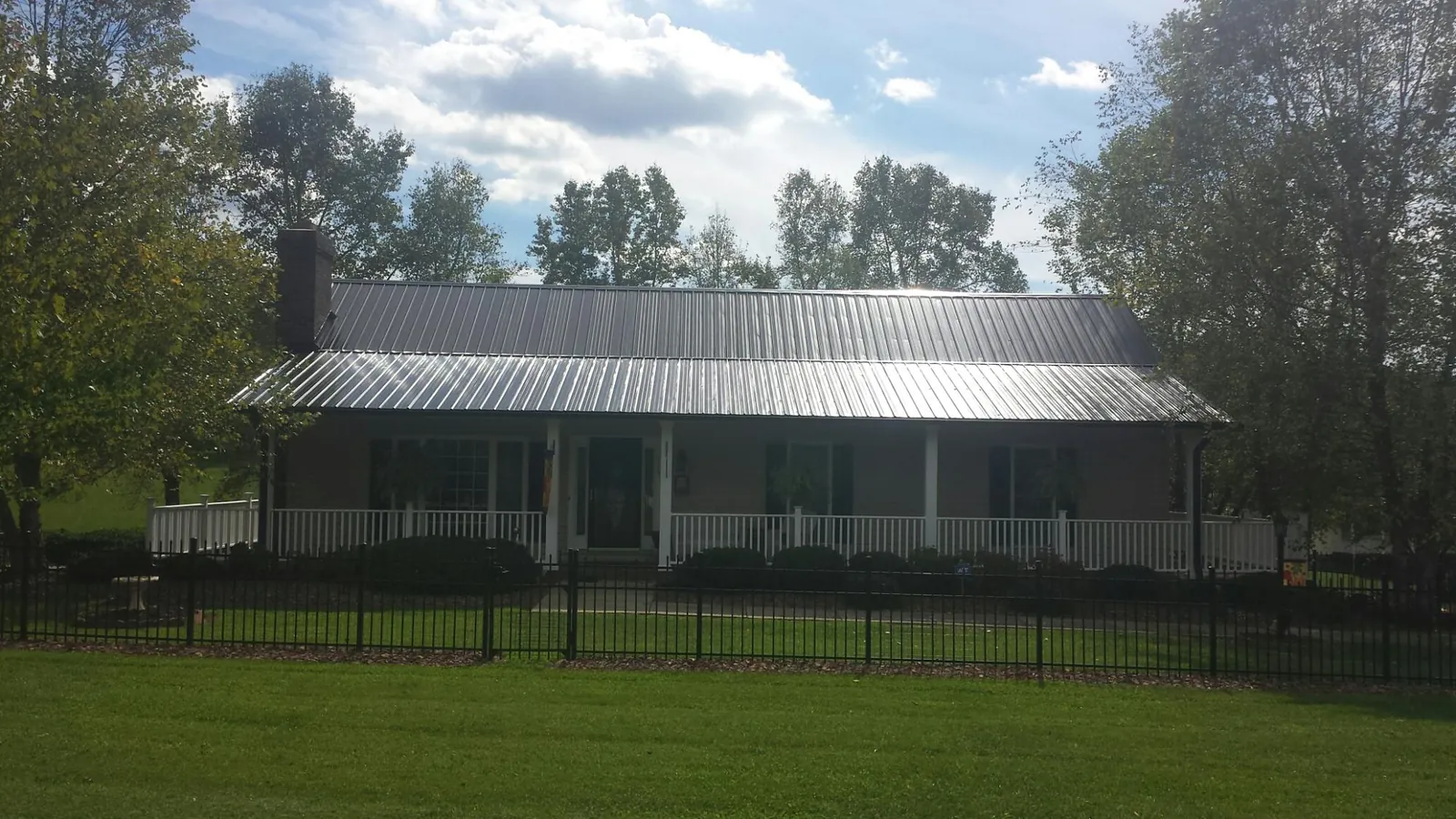 Gray metal roof on a brick ranch with a full width front porch — Gutter Guard Installation work by our crew in Desmet