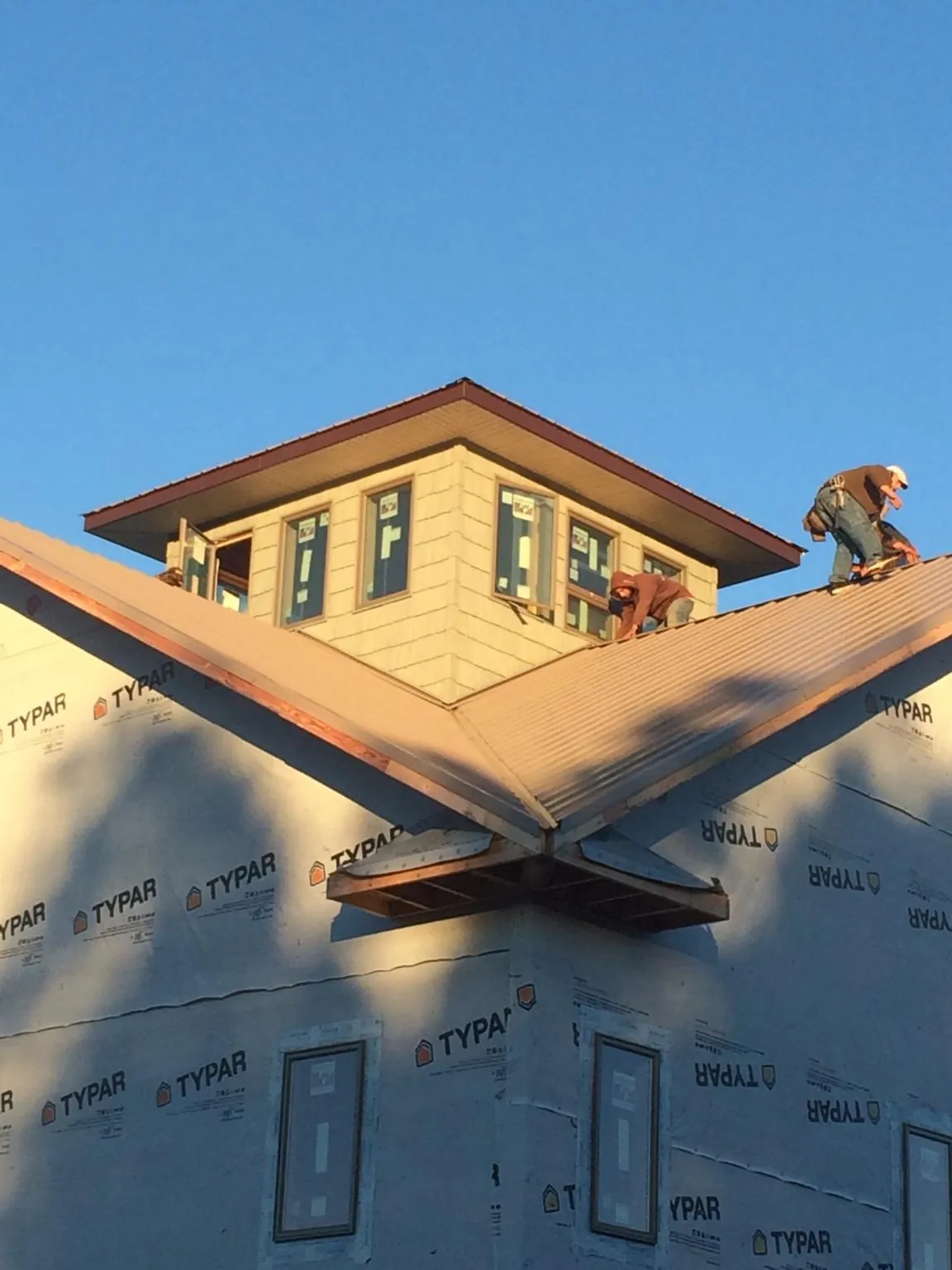 Roofers working around a rooftop cupola on a new metal roof at sunset — Roof Waterproofing in Desmet by Roofing Brothers